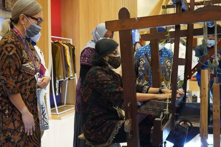 Menteri Keuangan Sri Mulyani mencoba menggunakan alat tenun bukan mesin di area pameran pertemuan G20 di Jakarta. 