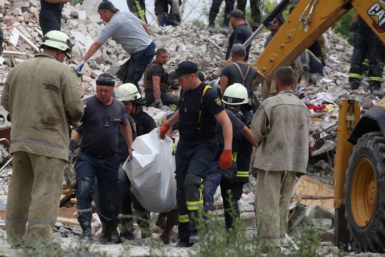 Tim penyelamat membawa mayat seorang pria setelah sebuah bangunan hancur sebagian setelah penembakan di Chasiv Yar, Ukraina timur, pada 10 Juli 2022.