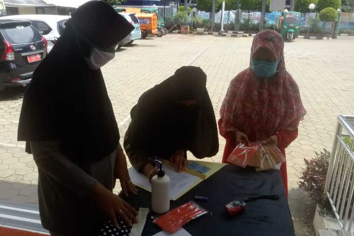 Warga mengambil masker gratis yang disediakan di Kantor Kelurahan Cipinang Melayu, Makasar, Jakarta Timur, Kamis (14/5/2020).
