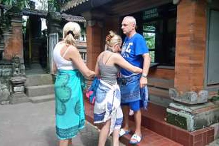 Wisatawan asing mengenakan kain yang disediakan petugas di Goa Gajah, Kabupaten Gianyar, Bali, Jumat (1/4/2016)