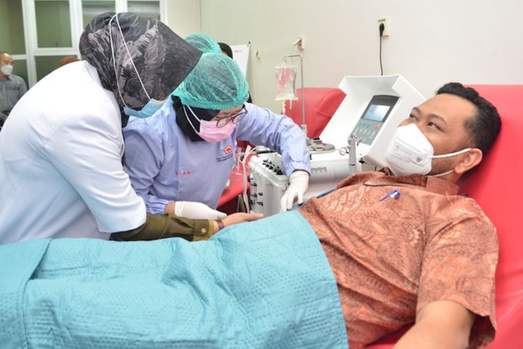 Bupati Gresik Fandi Akhmad Yani (kanan) saat berdonor darah plasma konvalesen di PMI Gresik, Rabu (16/6/2021).