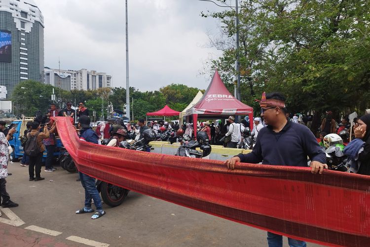 Pembentangan kain ulos sepanjang 1 kilometer di kawasan Monas, Gambir, Jakarta Pusat, Minggu (5/11/2023). (KOMPAS.com/XENA OLIVIA)