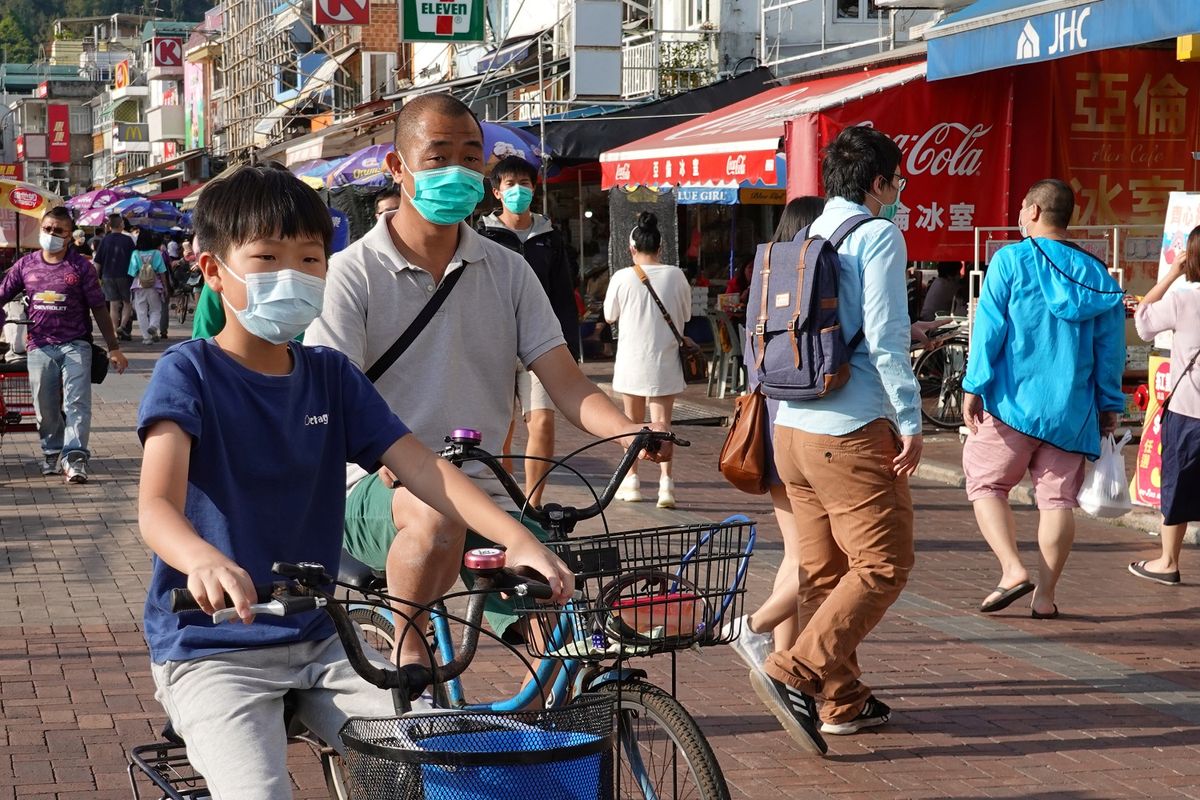 Warga Hong Kong terlihat memakai masker bepergian di pulau Cheung Chau saat libur Paskah, di tengah merebaknya virus corona. Foto diambil pada 12 April 2020.