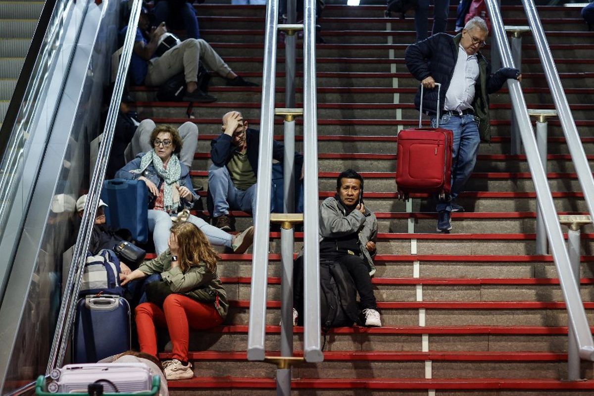 Para pelancong duduk di tangga saat bersiap untuk bermalam di stasiun kereta Atocha, menyusul pemadaman listrik massal yang memengaruhi seluruh semenanjung Iberia dan Perancis selatan, di Madrid pada 28 April 2025.
