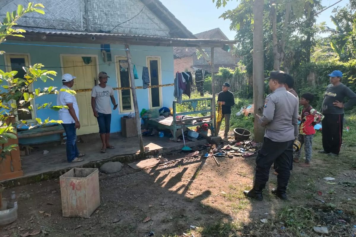 Polisi melakukan olah TKP dan memasang garis polisi di rumah KW.