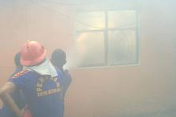 Petugas berusaha memadamkan api yang membakar kamar kos mahasiswi Akademi keperawatan Kendari, saat mereka mengikuti perkuliahan.   