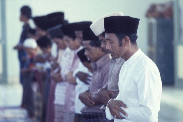 Muslim di Indonesia sedang salat dalam posisi berdiri, circa 1900.