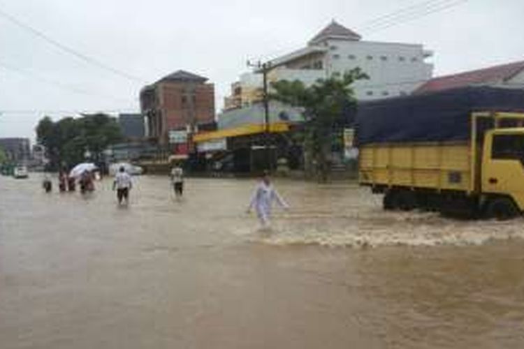 Anak-anak sekolah yang terpaksa dipulangkan akibat banjir. Mereka melintasi genangan di Jalan AW Sjahranie.