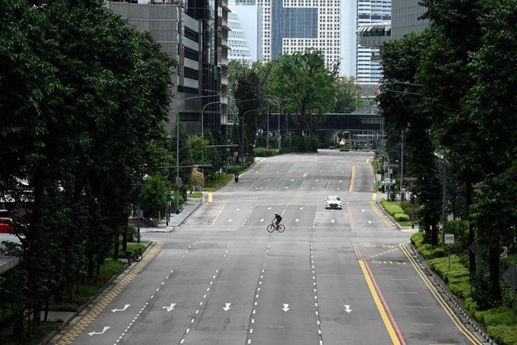 Pengendara sepeda mengendarai melintasi jalan yang tenang di kawasan pusat bisnis di Singapura.