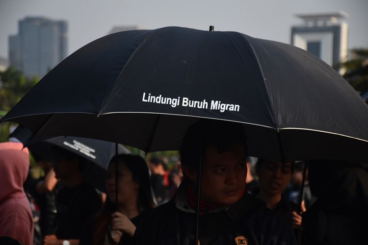Peserta acara rutin Kamisan di depan Istana Negara, Jakarta, tampak menggunakan payung dengan tulisan Lindungi Buruh Migran, Kamis (19/9/2019). 