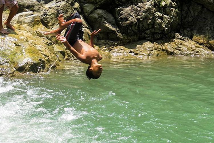 Seorang anak sedang salto di kolam alami Taman Sidandang, Purworejo.