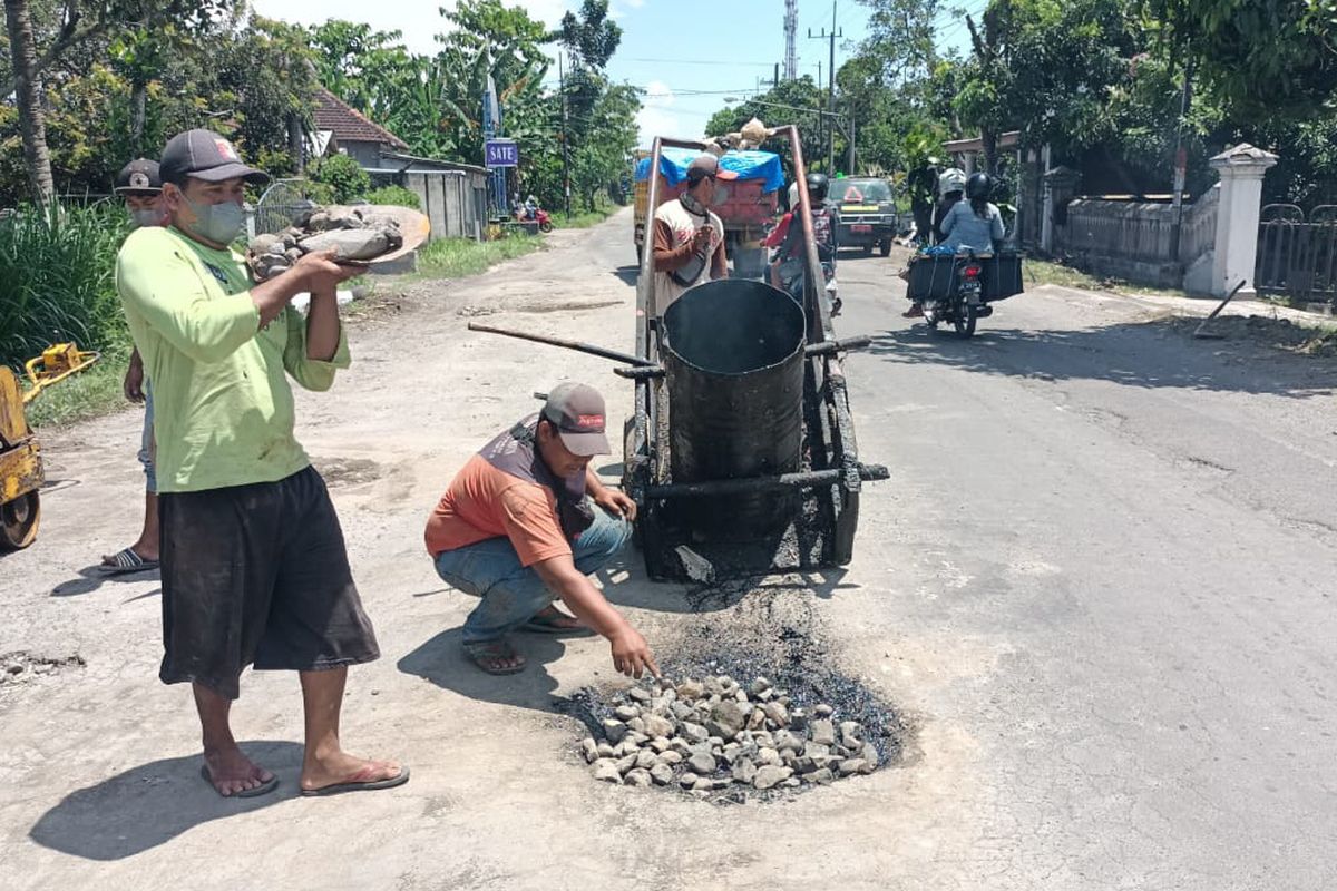 Pekerja Dinas PUPR Kabupaten Kediri memperbaiki jalan di Dusun Janti, Desa Janti, Kecamatan Wates, Minggu (3/4/2022). Jalan yang rusak itu sebelumnya dipasangi boneka baju hazmat oleh warga dan sempat viral.