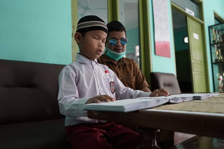 Salah satu penyandang tunanetra sekaligus guru honorer di Sekolah Luar Biasa (SLB) Budi Nurani, Kecamatan Baros, Kota Sukabumi, Jawa Barat (Jabar) bernama Ilham sedang mengajarkan salah satu anak didiknya membaca Al-Qur'an Braille.
