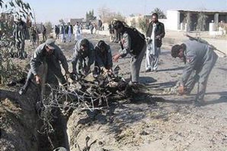 Polisi Afganistan mencoba mengangkat puing-puing kendaraan pelaku bom bunuh diri di sebuah lokasi serangan bunuh diri di Kandahar, 12 Desember 2007. 