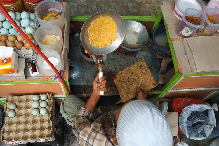 Pedagang kerak telor di Pekan Raya Jakarta tampak sibuk menyelesaikan pesanan pembeli.