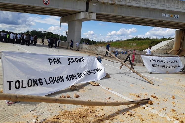 Warga memblokade Jalan Tol Balikpapan-Samarinda Kilometer 6 dengan membentangkan spanduk di tengah jalan di Balikpapan, Kalimantan Timur, Rabu (3/2/2022).