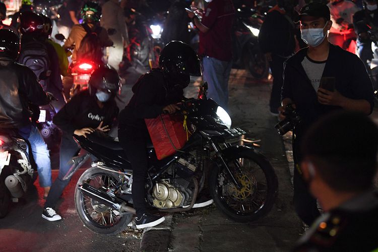Homecoming travelers move their motorbikes to the the opposite direction to avoid the security checkpoint in Kedungwaringin, Bekasi Regency, West Java, on Monday, May 10.