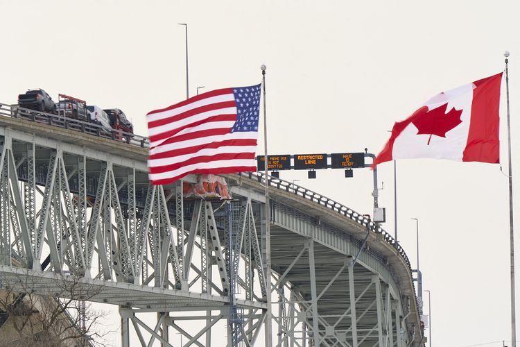 Bendera Amerika Serikat dan Kanada berkibar di sisi Sungai St Clair, dekat Jembatan Bluewater yang menghubungkan Sarnia di Ontario, Kanada, dengan Port Huron di Michigan AS, 29 Januari 2025.