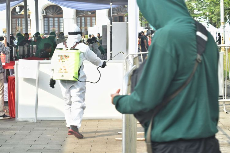 Petugas berpakaian APD tengah menyemprotkan disinfektan di pagar pembatas jalur keluar tempat tes massal yang digelar Badan Intelijen Negara (BIN) di Gedung Sate, Jalan Diponegoro, Kota Bandung, Jumat (26/6/2020). BIN membawa 40 orang tenaga medis dan dokter serta dua mobil laboratorium covid-19 dalam tes massal selama tiga hari di Bandung.