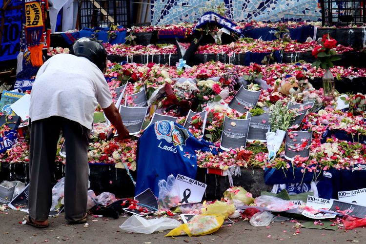Seorang laki-laki meletakkan tulisan ditumpukan bunga di hari kedua pasca tragedi yang terjadi pada pekan ke-11 Liga 1 2022-2023 seusai pertandingan bertajuk Derbi Jawa Timur, Arema FC melawan Persebaya Surabaya di Stadion Kanjuruhan Kepanjen, Kabupaten Malang, Senin (3/9/2022) siang.