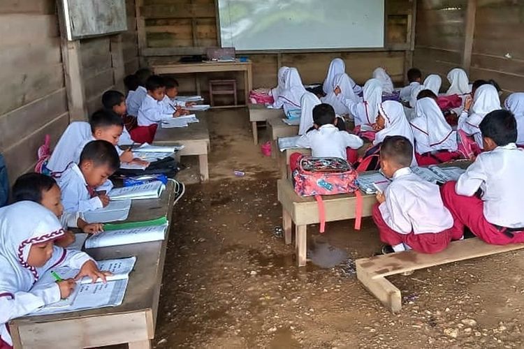 Para murid SDN 006 di Desa Ulak Patian, Kecamatan Kepenuhan, Kabupaten Rokan Hulu, Riau, sedang belajar di ruang kelas berdinding papan dan berlantai tanah.