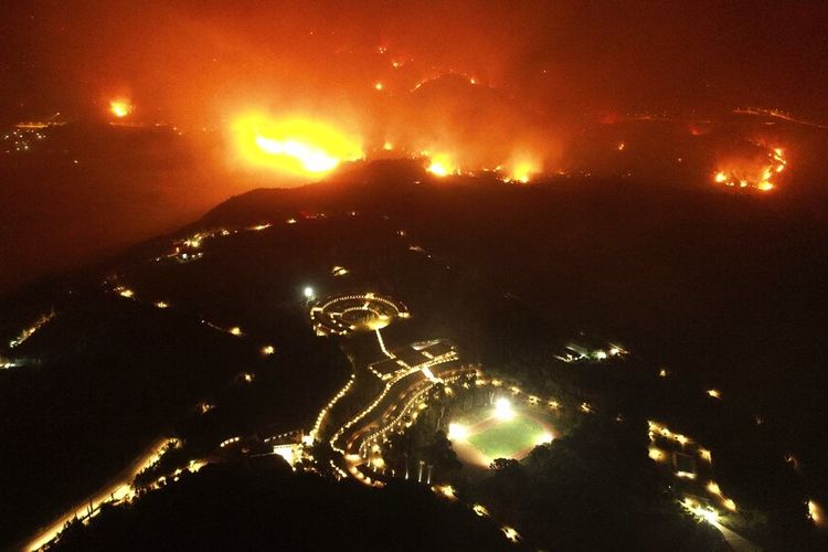 Kebakaran hutan mendekati Akademi Olimpiade, latar depan, di situs kuno Olympia, Rabu, 4 Agustus 2021. 