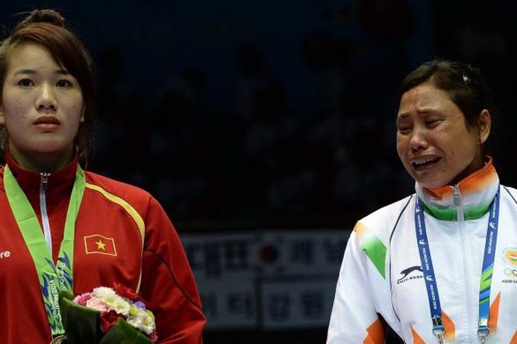 Sarita Devi (kanan) yang menangis di podium dan menolak mengenakan medali yang didapatkannya, Rabu (1/10/2014), sebagai protes atas penjurian yang menurut dia menyebabkan kekalahannya di babak semifinal tinju putri Asian Games 2014. 