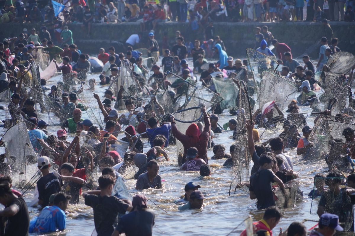 Warga berebut ikan dalam Festival Memet Ikan di Desa Gemblegan, Kecamatan Kalikotes, Klaten, Jawa Tengah, Minggu (20/7/2025).