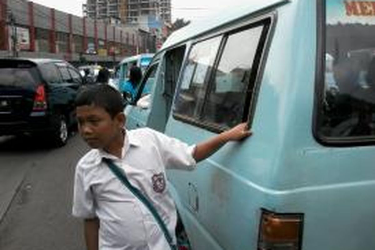 Joshua, bocah berusia 10 tahun yang saat ini sebagai pelajar Sekolah Dasar 19 Cipinang Muara, Jakarta Timur sedang mencari penumpang angkutan umum di Terminal Kampung Melayu, Jakarta Timur.