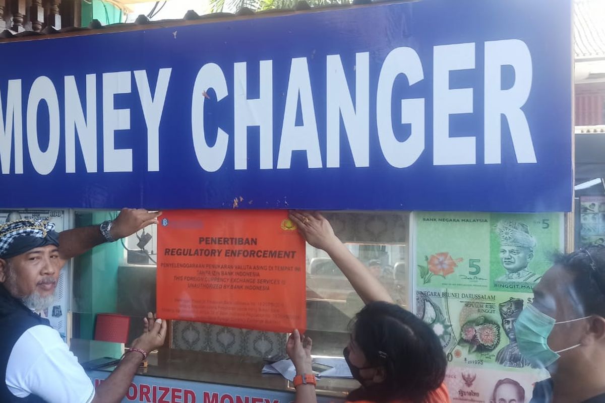 Manager Fungsi Pengawasan Sistem Pembayaran BI Bali, Ni Putu Sulastri bersama aparat setempat saat menempel stiker penertiban dari BI di salah satu money changer ilegal di Jalan Kartika Plaza, Tuban, Kuta, Badung, pada Kamis (4/8/2022). Kompas.com/ Yohanes Valdi Seriang Ginta