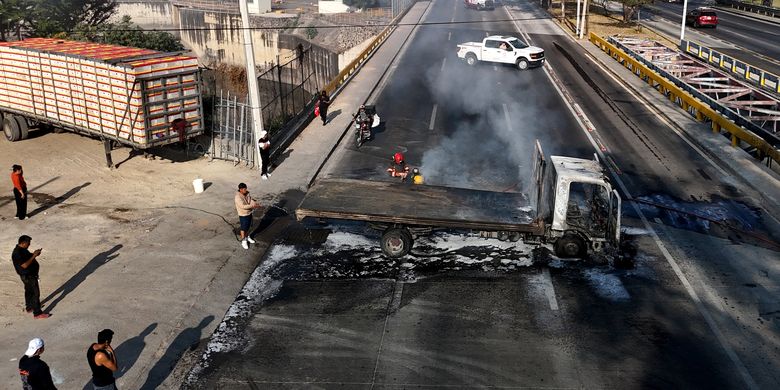 Petugas memadamkan api di truk yang dibakar kelompok kriminal sebagai balasan tewasnya bos kartel narkoba Jalisco, Nemesio El Mencho Oseguera, di salah satu jalan utama di Zapopan, Negara Bagian Jalisco, Meksiko, Minggu (22/2/2026).