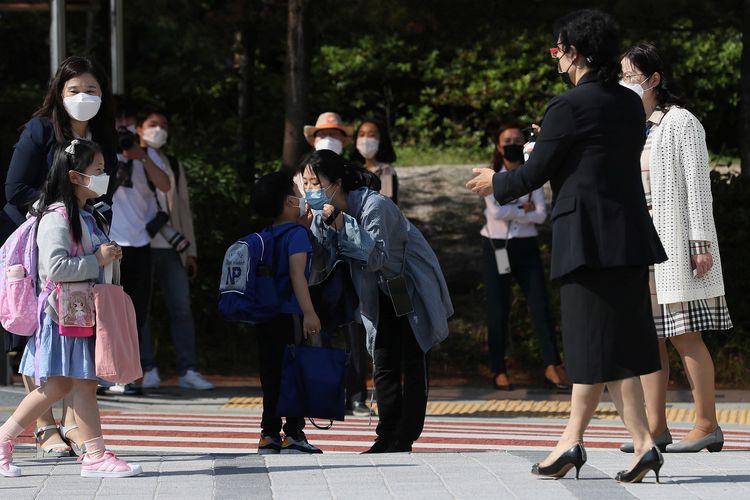 Seorang ibu mencium anaknya, di mana mereka menggunakan masker untuk menghindari penularan virus corona di TK di Seoul, Korea Selatan, pada 27 Mei 2020.