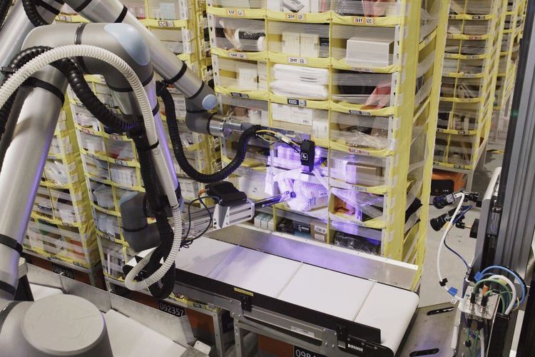 Robot Vulcan yang sedang mengambil barang di suatu rak.
