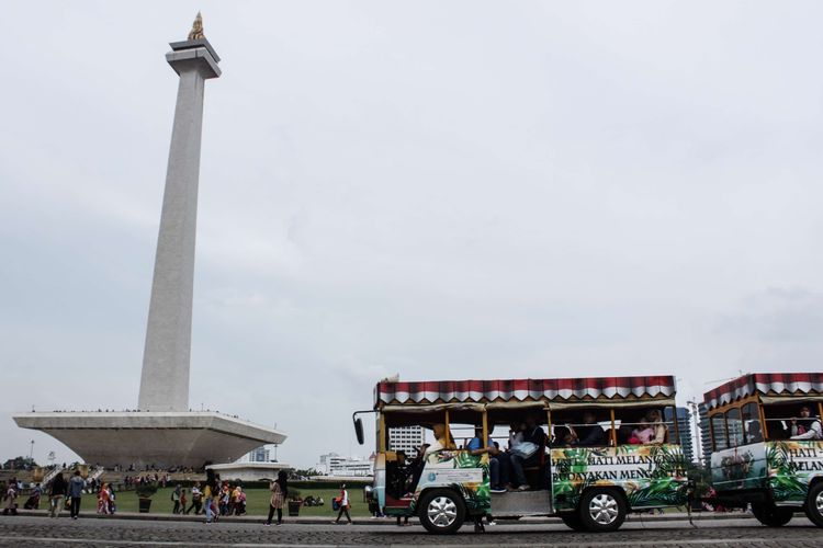 Pengunjung menaiki kereta wisata yang disediakan oleh pengelola guna mengelilingi kawasan Monumen Nasional, Gambir, Jakarta Pusat, Minggu (29/12/2019). Jelang penghujung 2019, tempat wisata Monumen Nasional (Monas) ramai dikunjungi wisatawan lokal maupun mancanegara.