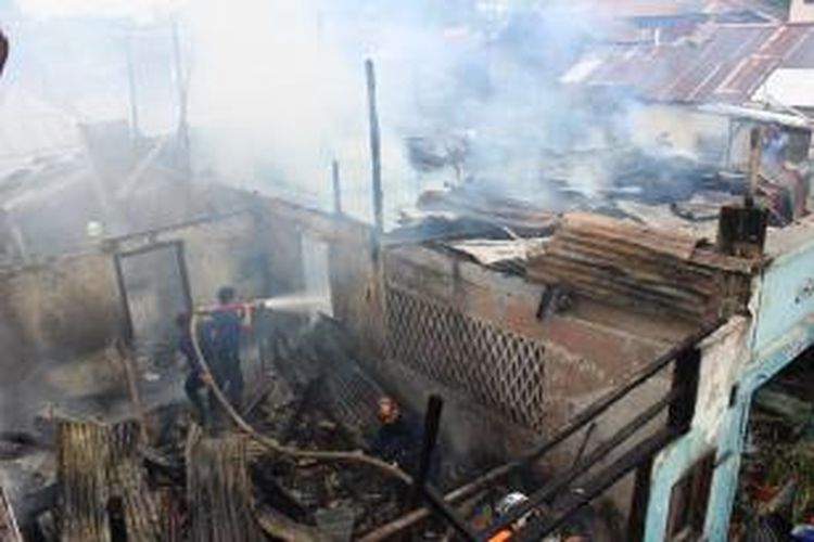 Petugas pemadam kebakaran sedang berupaya untuk memadamkan sisa-sisa api akibat kebakaran yang meludeskan rumah warga di Manado.