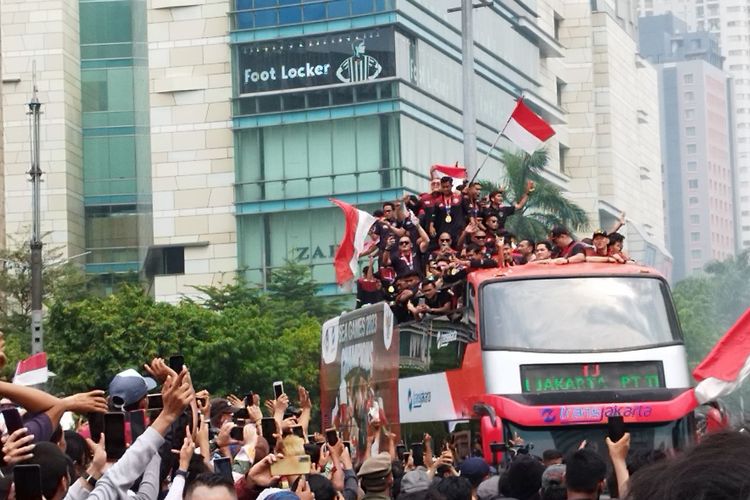 Warga melambaikan tangan menyambut kedatangan konvoi Timnas sepakbola U-22 di Bundaran HI, Menteng, Jakarta Pusat, Jumat (19/5/2023). (KOMPAS.com/XENA OLIVIA)