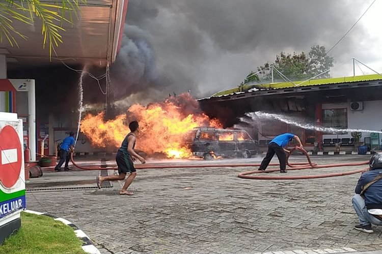 Petugas pemadam kebakaran dan petugas SPBU Desa Larangan Badung, berusaha memadamkan api yang membakar mobil bermuatan bensin.