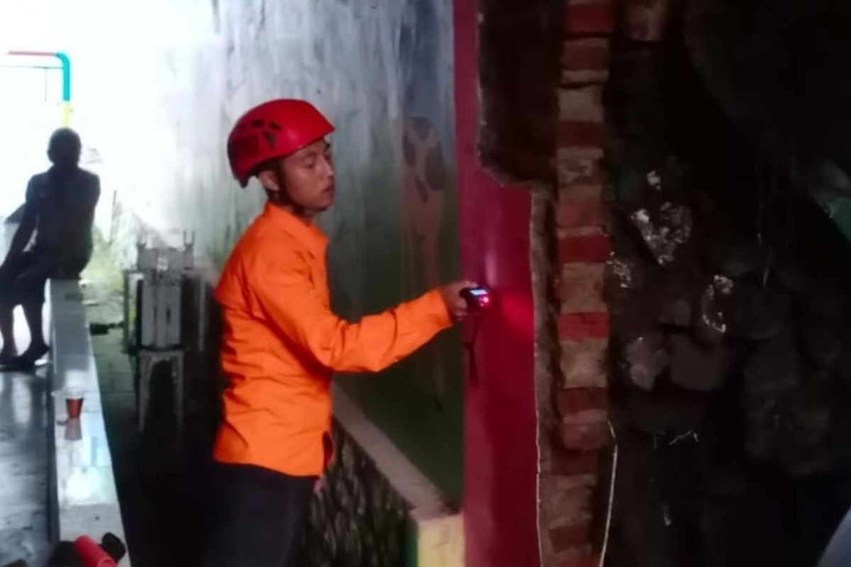 Tembok sebuah rumah dan benteng bangunan sekolah di Kelurahan Citeureup, Kecamatan Cimahi Utara, Kota Cimahi, Jawa Barat jebol usai diterjang pergerakan tanah, Senin (2/1/2024).