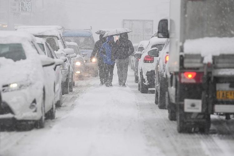 orang-orang berjalan di tengah jalan saat salju turun di Agios Steganos, utara Athena, pada 24 Januari 2022. 