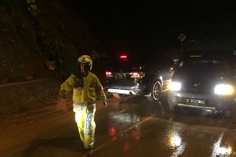 Petugas Satuan Lalu Lintas Polres Bandung tengah mengatur arus kendaraan di lokasi longsor di jalur yang menghubungkan Bandung-Pangalengan, Senin (19/2/2018).