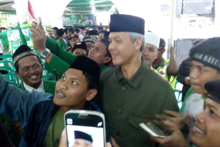 Gubernur Jateng,  Ganjar Pranowo,  saat melayani swa foto , seusai acara pelantikan pengurus Pimpinan Wilayah Gerakan Pemuda Ansor Jateng dan Pimpinan Cabang Gerakan Pemuda Ansor Demak,  di Pondok Pesantren Girikusumo, Mranggen, Demak,  Sabtu (27/1/2018) sore.