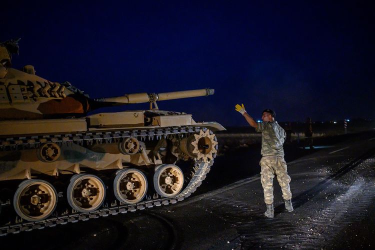 Seorang tentara Turki mengarahkan tank menuju perbatasan Suriah dekat kota Akcakale di Provinsi Sanliurfa pada 8 Oktober 2019. Turki menyatakan mereka siap menggelar serangan ke utara Suriah untuk menargetkan milisi Kurdi.