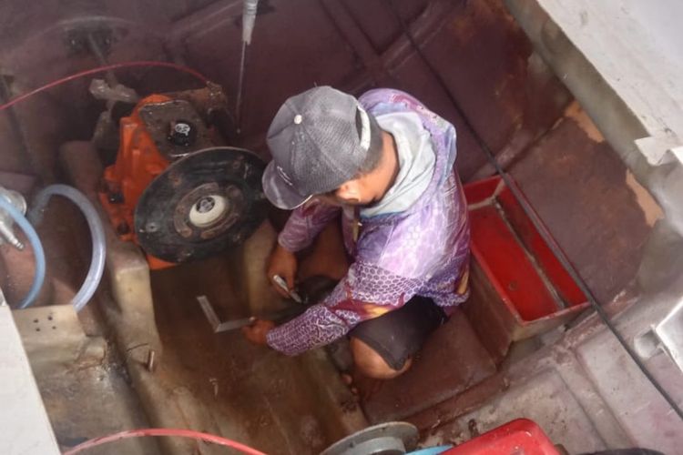 Foto: Seorang nelayan di Sikka sedang memperbaiki mesin kapal bantuan Kemensos yang rusak.