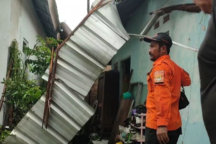 Sejumlah Petugas BPBD melakukan perbantuan terhadap rumah yang rusak setelah ditimpa pohon besar yang tumbang usai angin kencang dan hujan deras melanda Desa Klangenan Kecamatan Klangenan Kabupaten Cirebon Jawa Barat, pada Rabu (13/3/2024) petang