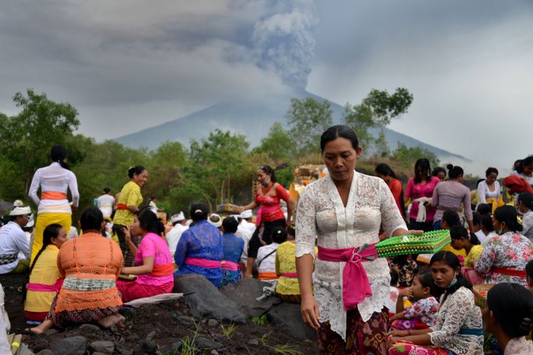 Warga Bali menjalankan ritual doa di depan saat  terjadi erupsi Gunung Agung di Desa Muntig, Kubu, Karangasem, Bali, 26 November 2017. Gunung Agung terus menyemburkan asap dan abu vulkanik dengan ketinggian yang terus meningkat, mencapai ketinggian 3.000 meter dari puncak. Letusan juga disertai dentuman yang terdengar sampai radius 12 kilometer.