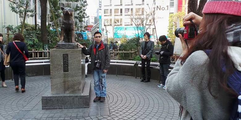 Seorang wisatawan berfoto di samping patung anjing Hachiko di dekat Stasiun Shibuya, Tokyo, Jepang.