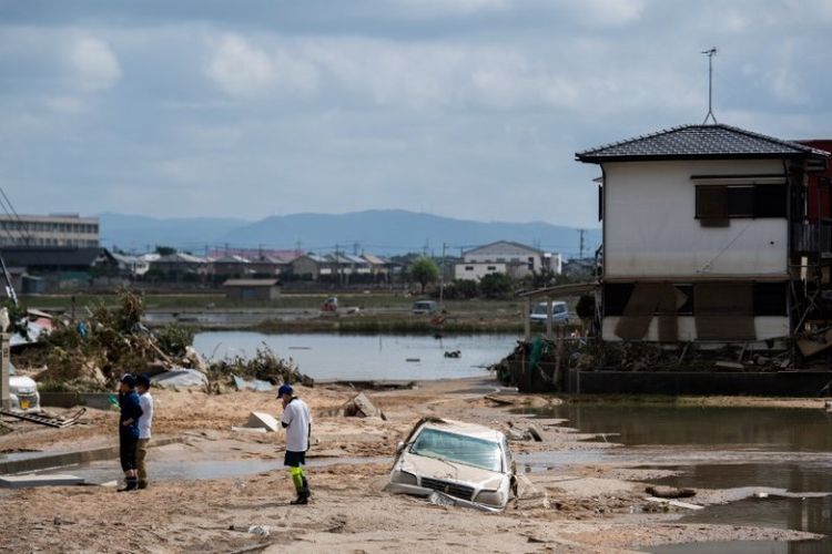 Penduduk memeriksa rumah mereka yang rusak akibat banjir di Mabi, Prefektur Okayama, Selasa (10/7/2018). (AFP/Martin Bureau)