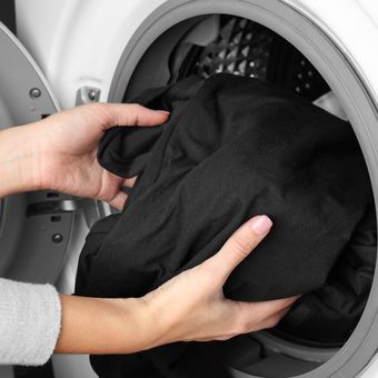Ilustrasi mencuci baju hitam menggunakan mesin cuci
