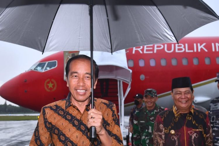 Presiden Joko Widodo memegang payung sendiri saat baru mendarat di Bandara Internasional Syamsudin Noor, Kota Banjarbaru, Provinsi Kalimantan Selatan (Kalsel), pada Kamis (16/3/2023).