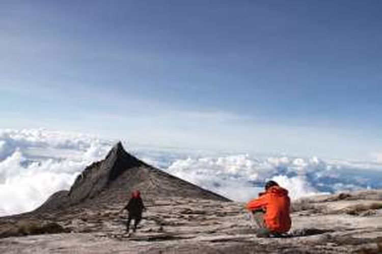 Pendaki berfoto dengan latar belakang South Peak, Gunung Kinabalu, Sabah, Malaysia (22/11/2016). Gunung Kinabalu sendiri berstatus gunung tertinggi di Pulau Kalimantan dan berada di bawah pengelolaan Kinabalu Park. Gunung Kinabalu berketinggian 4.095,2 meter di atas permukaan laut (mdpl).